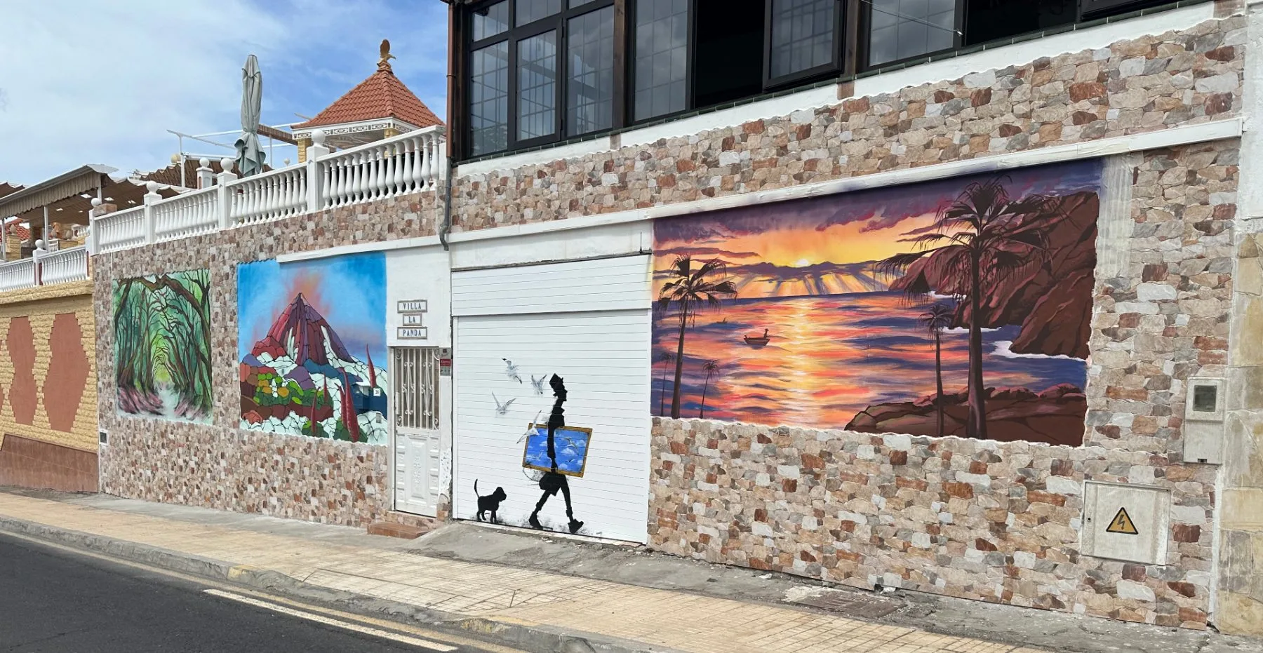 Tres murales de María en un muro exterior, vistos desde la calle