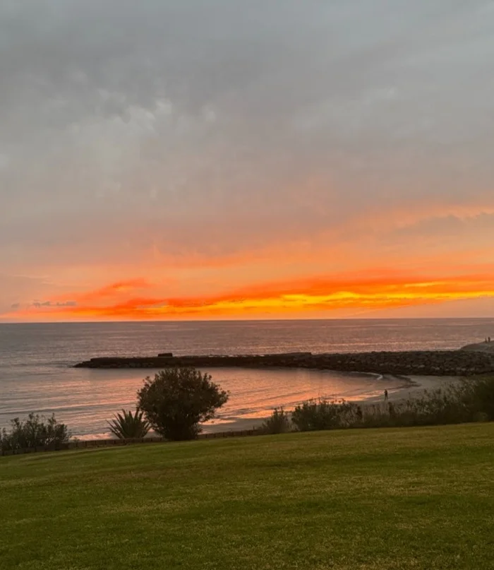 Poniente de ceniza rosa y naranja sobre la bahía