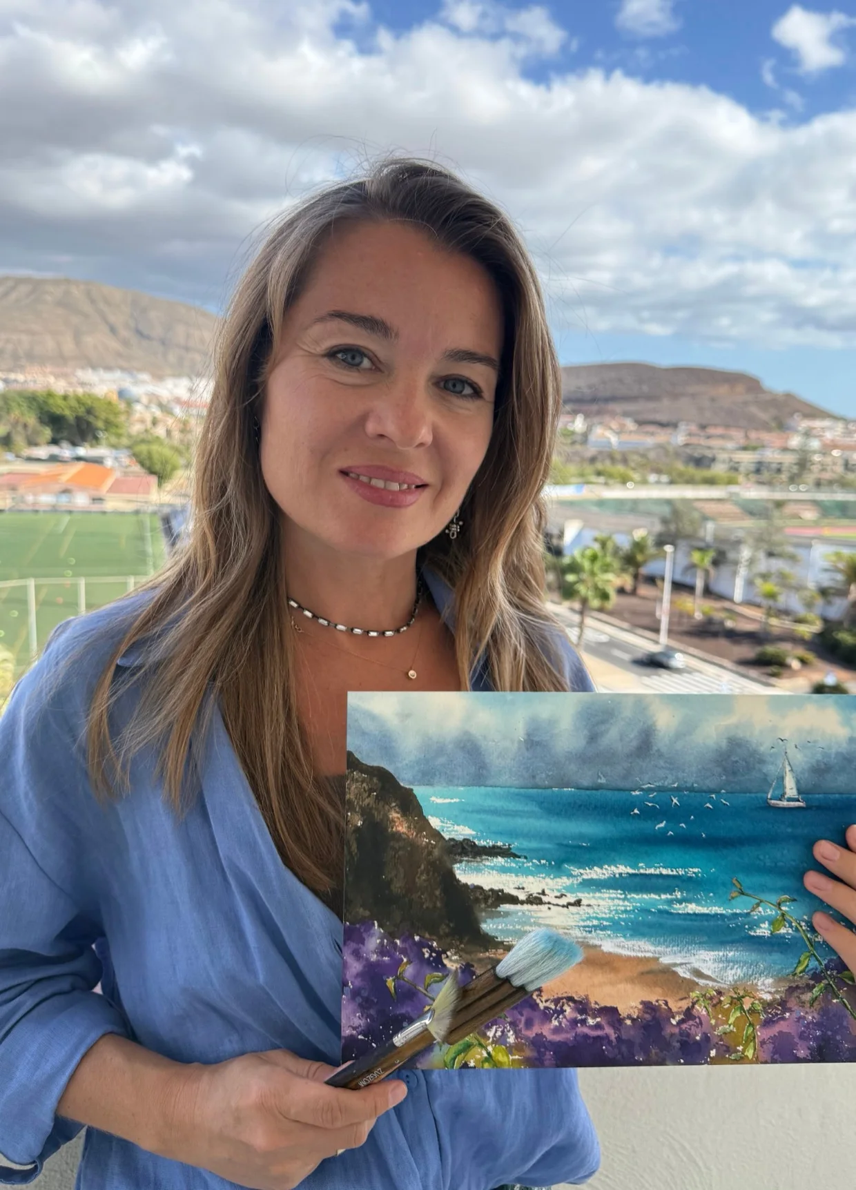 María Vozniak sostiene una de sus marinas en la terraza del estudio, con la costa de Tenerife detrás
